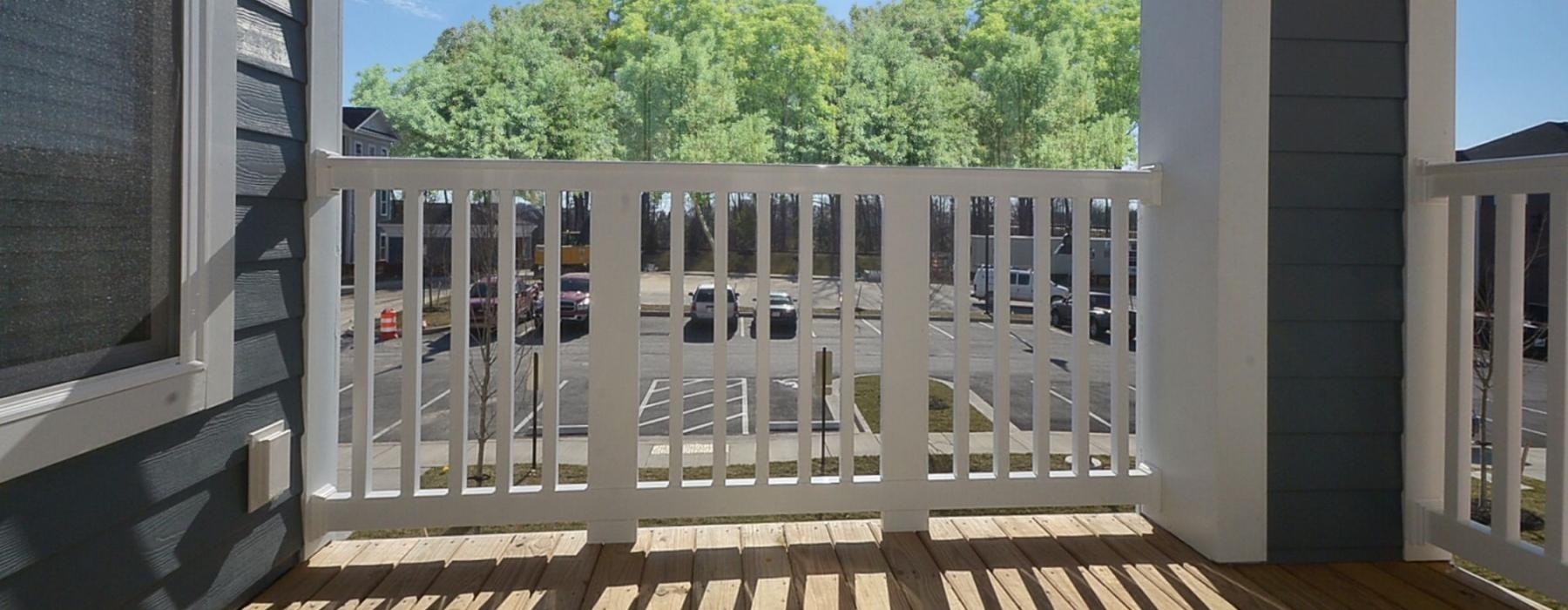 a deck with a railing and trees in the background